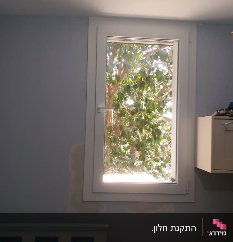 חלון עם קיר צבוע חלקית בתהליך שיפוץ